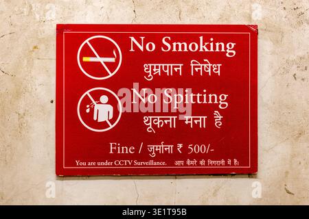 Ein rotes Schild in Udaipur zeigt Anweisungen zum Rauchen und Spucken auf Englisch und Hindi, einschließlich Informationen über eine Geldstrafe und CCTV. Stockfoto