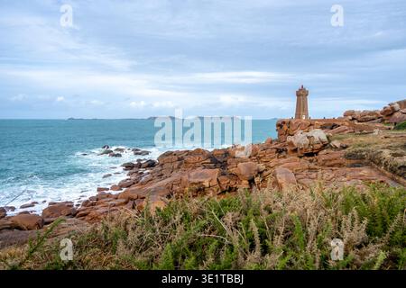 Der Leuchtturm Mean Ruz steht markant über der Granitküste von Tregastel an der Pink Granite Coast in der Bretagne, Frankreich, umgeben von Wellen und Stockfoto