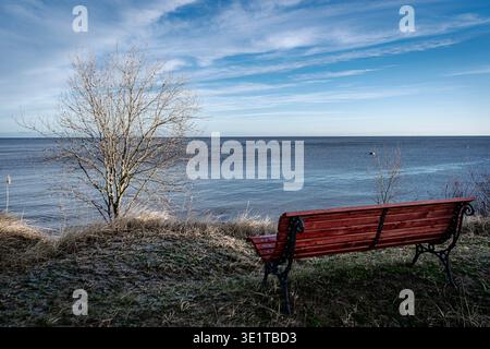 Leere rote Bank mit Blick auf die Ostsee in der kalten Jahreszeit Stockfoto