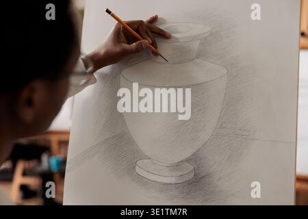 Afroamerikanischer Guy Student, der Zeichenfähigkeiten verbessert und an einem Kunstworkshop teilnimmt. Nahaufnahme eines Mannes, der Bleistift hält und Bleistiftschattiertechniken praktiziert, wobei er sich auf den Prozess des Skizzierens konzentriert Stockfoto