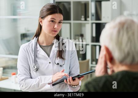 Junge Ärztin Berät Senior Männlicher Patient Stockfoto