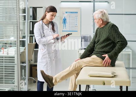 Junge Ärztin untersucht Seniorenmann in der Klinik Stockfoto