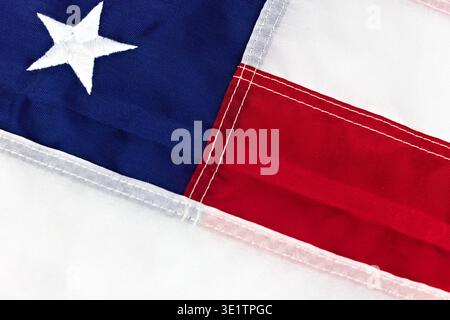 Eine extreme Nahaufnahme der US-Flagge, die den gestickten weißen Stern auf einem blauen Feld und die roten und weißen Streifen mit sichtbaren Nähten hervorhebt Stockfoto