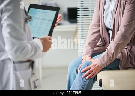 Erwachsene Frau Beratungsarzt über Knieschmerzen in der Klinik Stockfoto