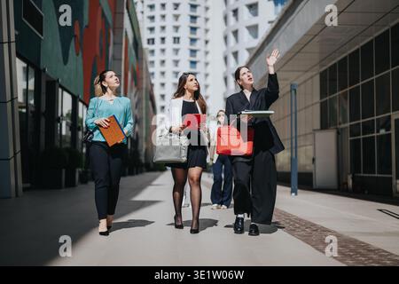 Drei Berufstätige laufen und diskutieren über Arbeit in einem städtischen Geschäftsviertel Stockfoto