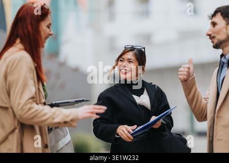 Drei Geschäftsleute lächeln und unterhalten sich bei einem Treffen im Freien auf der Stadtstraße Stockfoto
