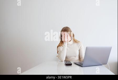 Gestresste Frau, die am Laptop arbeitet und frustriert den Kopf hält. Burnout bei Remote-Arbeit, Online-Probleme und Überlastungskonzept. Stockfoto