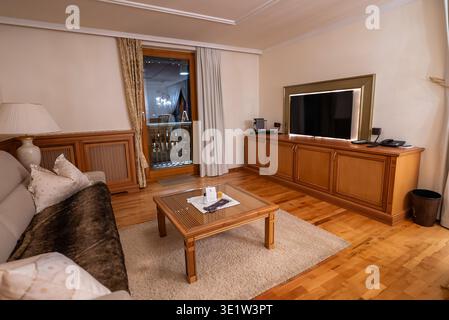 Warm beleuchtetes alpines Hotelzimmer mit Balkon und Bergblick Stockfoto