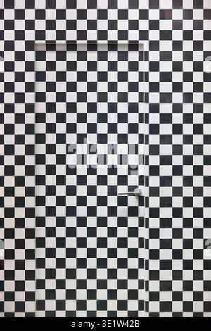 Tür und Wand in Schwarz-weiß gestrichen. Optischer Effekt Stockfoto