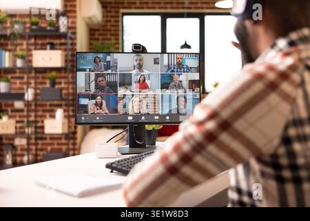 Schwarzer Mann, der an einem virtuellen Webinar unter multiethnischen Fachleuten auf Desktop-pcs teilnimmt. afroamerikanischer Mann, der einen Computer für Videoanrufe mit Kollegen aus der Ferne benutzt. Stockfoto