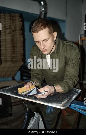 Vertikal des jungen Mannes, der Farbfelder bei der Arbeit in Innenräumen vergleicht Stockfoto