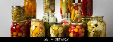 Canning ist eine häufige Aktivität in der Küche, da die Theke mit Gemüse und Obst gefüllte Gläser säumen. Diese Praxis hilft dabei, Lebensmittel für den Gewinn zu bewahren Stockfoto