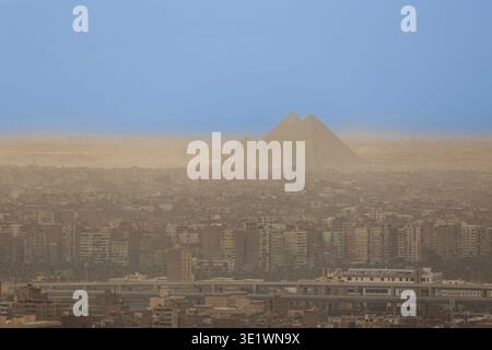 Aus der Vogelperspektive von Kairo mit den Pyramiden von Gizeh am Horizont, die dichte Stadtviertel, Wüstenlandschaft und den Kontrast zwischen Moderne zeigen Stockfoto