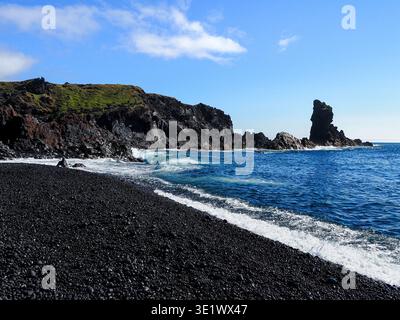 Wunderschöner Strand von Djupalonssandur. Gelegen an der Südküste Islands. Basaltgesteinsformationen und schwarzer nasser Sand und Kieselsteine. Blauer Atlantik. Stockfoto