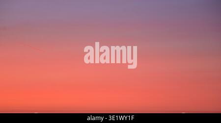 Atemberaubender, dramatischer Himmel mit intensiven Orange-, Rot- und Violetttönen, während Wolken die kräftige Nachmittagssonne einfangen. Stockfoto