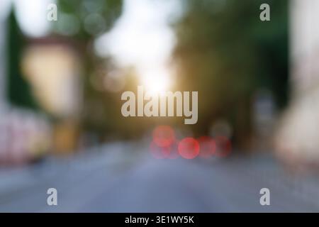 Abstrakter Blick auf eine Straße mit verschwommenen roten Rücklichtern und einem sanften Sonnenlicht schaffen eine traumhafte Atmosphäre Stockfoto