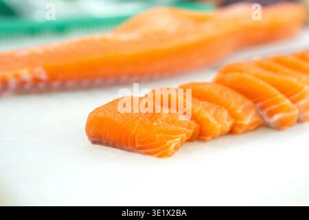 Hochwinkelaufnahme von geschnittenen Atlantischen Lachsfilets, zubereitet für Sushi oder Sashimi auf einer sauberen Küchenoberfläche. Stockfoto