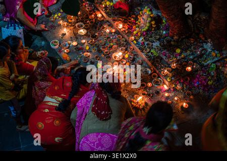 Frauen in farbenfrohen Saris knien in Udaipur auf dem Boden, um während einer traditionellen religiösen Zeremonie in der Nacht zahlreiche kleine Öllampen anzuzünden. Udaipur Ra Stockfoto