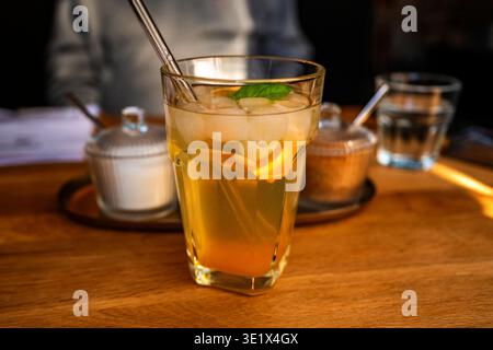 Ein Glas Orangenlimonade, zwei Zuckerschalen (mit weißem und braunem Zucker), ein Glas Wasser, Kaffee auf dem Tisch. Stockfoto