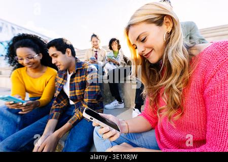 Verschiedene junge Studentenfreunde nutzen gemeinsam Smartphones im Freien Stockfoto