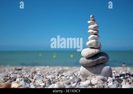 Ein Haufen ausgeglichener Steine an einem Kiesstrand. Ein Symbol für Frieden, Gelassenheit und Meditation Stockfoto