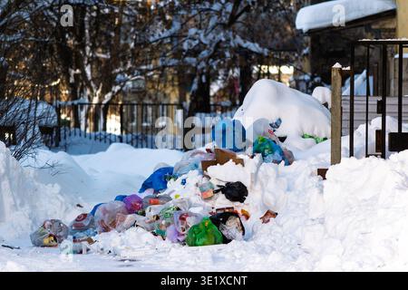 Ein unordentlicher Haufen von Siedlungsmüll, Plastiktüten und weggeworfenem Müll steht im Kontrast zu reinweißem Winterschnee und zeigt Umweltvernachlässigung: Russland - Stockfoto