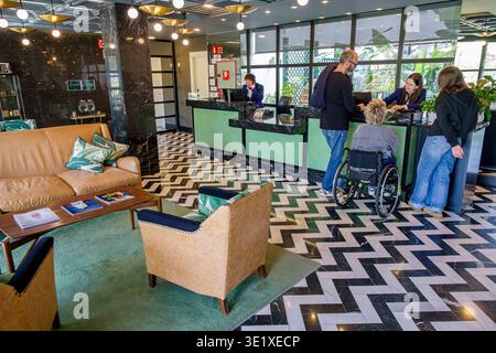 Malaga Spanien, Andalusien Andalusien, Hotellobby Rezeption Gäste, die sich für Rollstuhlfahrer und Behinderte einchecken, einschließlich Hilfe des Reisepersonals Stockfoto