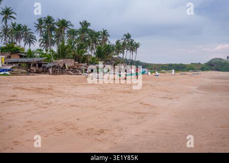 Offener Sandstrand mit Palmen und fernen Hügeln, der eine friedliche tropische Landschaft in Palawan, Philippinen, schafft. Stockfoto