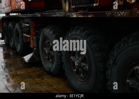 Ein professionelles, flaches Foto mit Schwerpunkt auf den massiven mehrachsigen Rädern eines Industriekrans. Die Szene erfasst die robuste Textur des tir Stockfoto