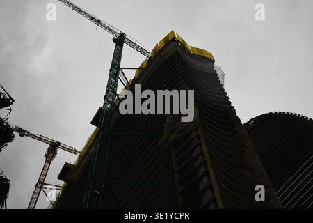 Eine professionelle architektonische Aufnahme, die die dramatische Silhouette eines im Bau befindlichen Hochhauses festnimmt. Das Bild ist grün und gelb bis Stockfoto