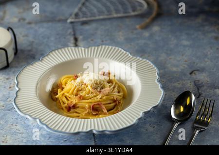 Spaghetti Carbonara serviert mit Speck, Käse und frischer Pasta auf rustikalem blauen Tisch Stockfoto