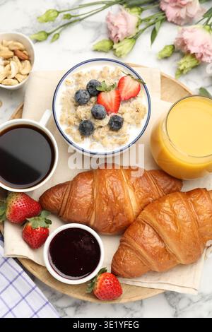 Gesundes Frühstück. Flache Komposition mit leckeren Croissants und Haferbrei mit Beeren auf weißem Marmortisch Stockfoto