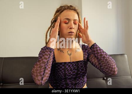 Junge Frau mit Dreadlocks und Tattoos, die an einer schweren Migräne leidet Stockfoto