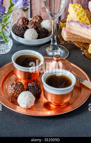 Kaffee und eine Auswahl an Gourmet-Kuchen und Schokoladentrüffeln auf einem Tisch Stockfoto