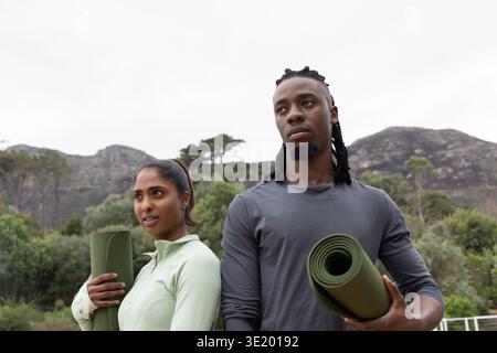 Verschiedene Paare mit gerollten grünen Yogamatten, die in sportlicher Kleidung auf dem Trail stehen Stockfoto