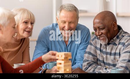 Freunde genießen ein Jenga-Spiel bei einer gemütlichen Zusammenkunft in einem hellen Wohnzimmer Stockfoto
