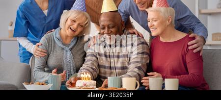 Eine Gruppe von Freunden feiert einen Geburtstag zu Hause mit Kuchen und Getränken am Nachmittag Stockfoto