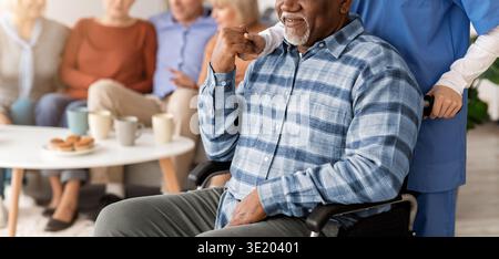 Ein älterer Mann lächelt, während er tagsüber in einer Pflegeeinrichtung Hilfe erhält Stockfoto