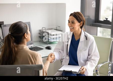 Junge Ärztin schüttelt mit weiblicher Patientin die Hand Stockfoto