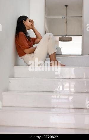 Frau in emotionaler Not, die allein auf der Treppe sitzt Stockfoto