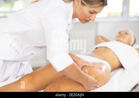 Nahaufnahme einer jungen Frau, die eine Oberschenkelmassage bekommt Stockfoto