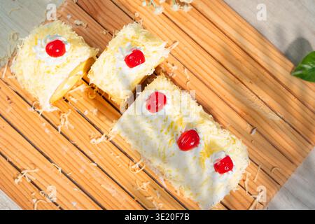 Köstlicher Schweizer Brötchenkuchen mit geriebenem Käsefrosting und Kirschgarnitur auf Einem Holzbrett Stockfoto