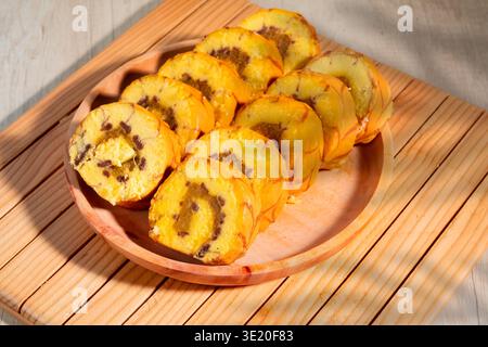 Süße Schweizer Rolltortenscheiben glasiert mit Honig- und Schokoladenfüllung auf Holzplatte Stockfoto