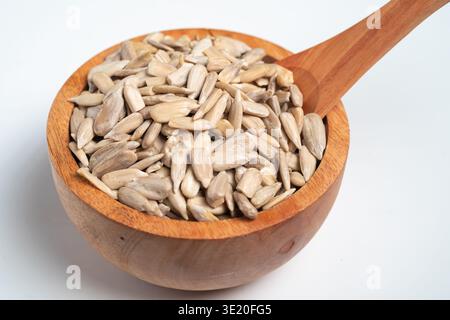 Holzschüssel gefüllt mit Sonnenblumensamen und Einem Holzlöffel auf weißem Hintergrund Stockfoto