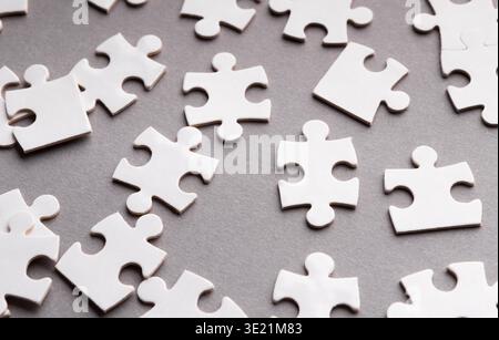 Sammlung leerer Puzzleteile auf einer grauen Oberfläche, angeordnet in einem zufälligen Muster Stockfoto
