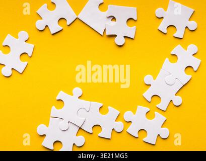 Mosaik aus weißen Puzzleteilen auf einem leuchtend gelben Hintergrund für kreative Projekte Stockfoto