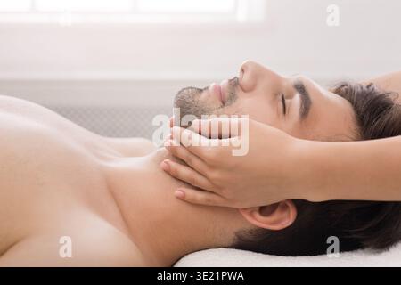 Gutaussehender Mann, der professionelle Gesichtsmassage im Salon bekommt Stockfoto