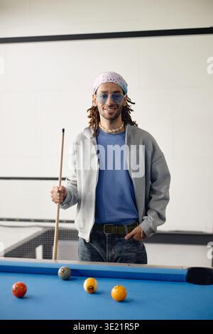Vertikal des lächelnden jungen Erwachsenen, der mit Billard Cue lächelt Stockfoto