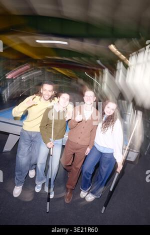 Vertikal der verschiedenen Gruppe von jungen Erwachsenen, die lächelnd und posierend sind und Pool-Signale halten Stockfoto