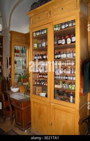 Antike hölzerne Apothekenschrank gefüllt mit alten Apothekenflaschen und Glasgläsern in einem historischen Laborbereich. Stockfoto